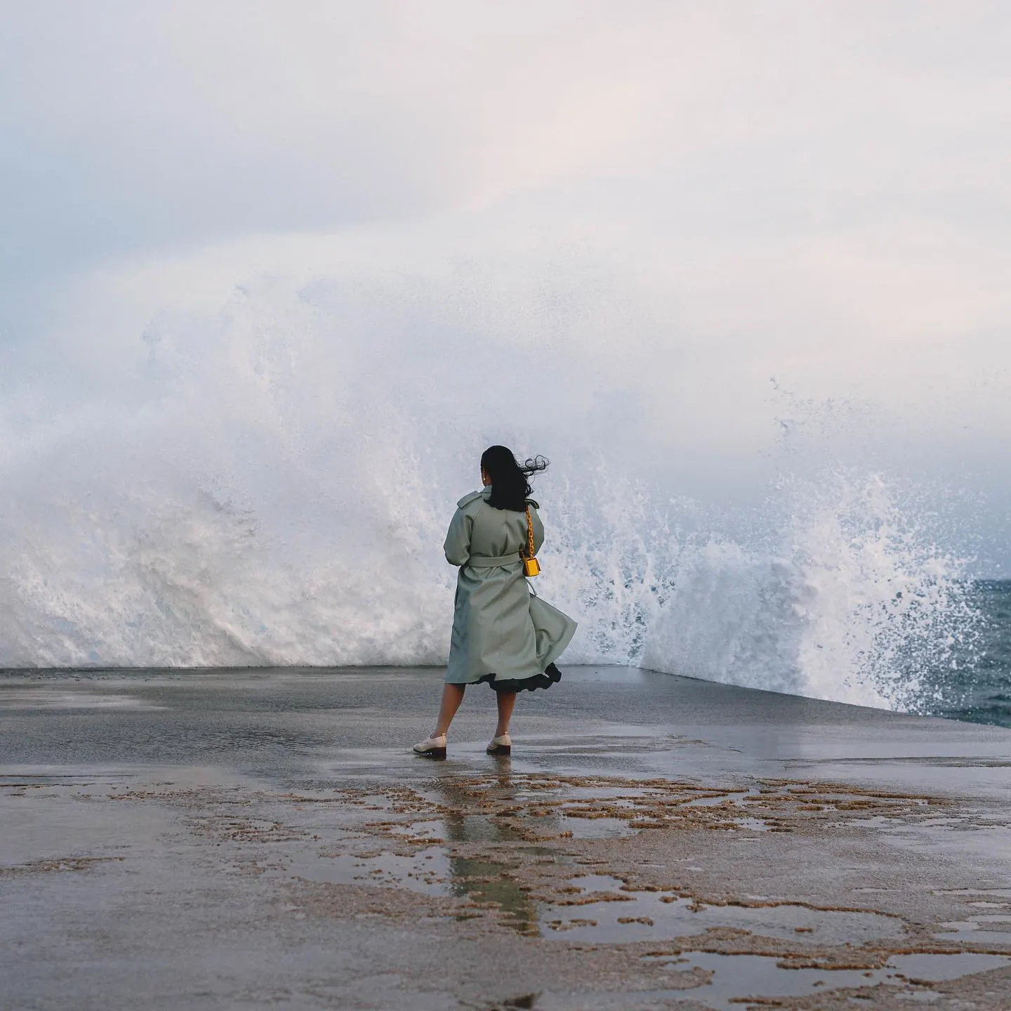 Woman standing in front of a breaking ocean wave